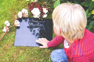 Pojke vid gravsten med blomma Muskat