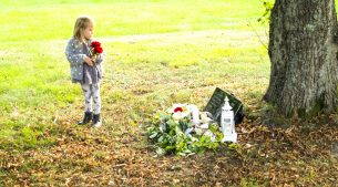 Flicka lägger rosor på gravplats hund