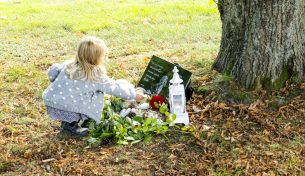 Flicka lägger blommor på gravplats hund
